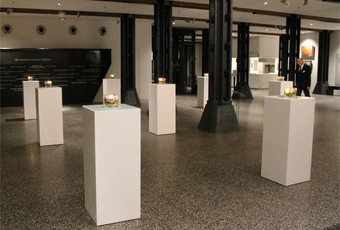 Säulenstehtisch weiß im eleganten Eventraum mit Glasplatte und Blumendekoration