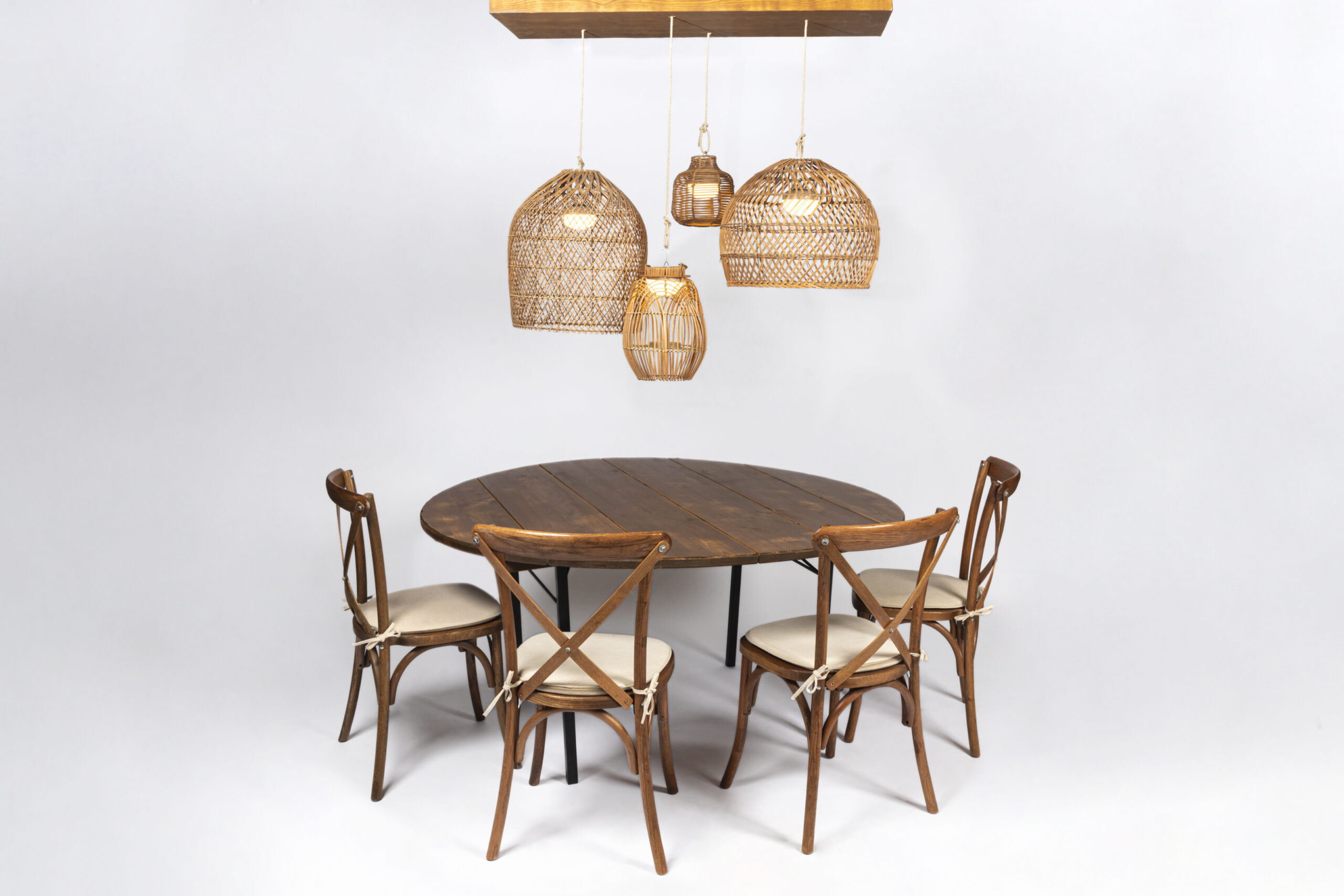 Sitzkissen Crossback auf Holzstühlen an runder Tafel mit Rattanleuchten