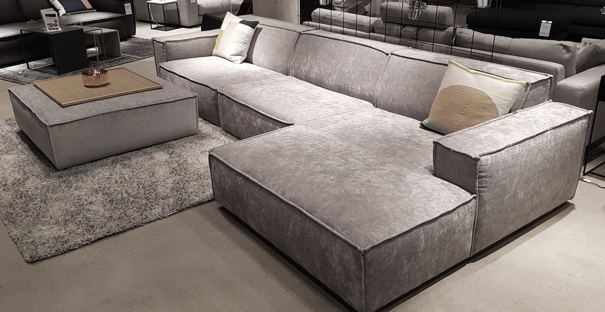 Modul-Hocker Manhattan vor grauer Ecksofa-Landschaft im Showroom