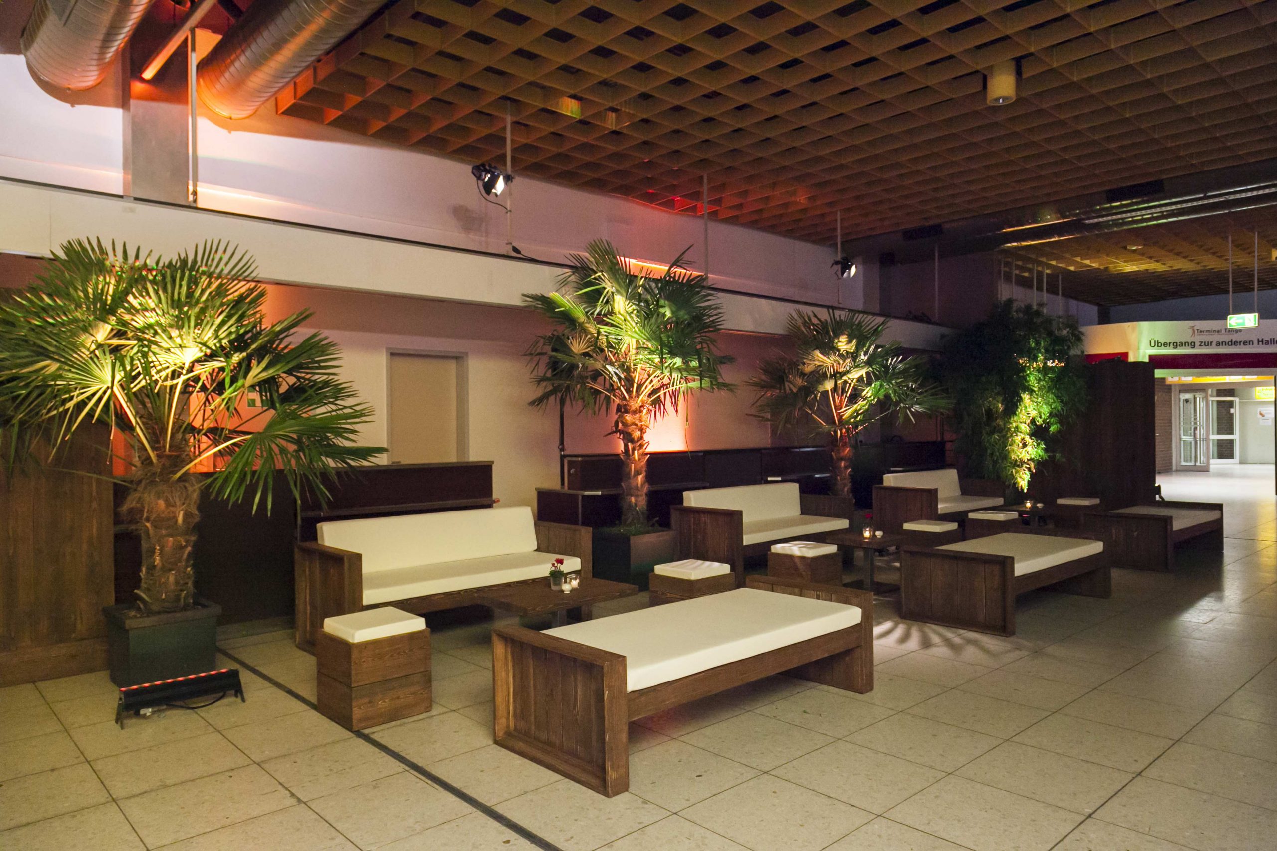 Sommer / Palmen in beleuchteter Eventlounge mit weißen Sitzmöbeln