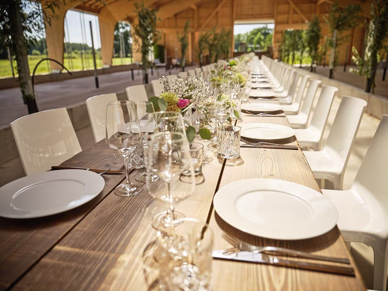 Festlich gedeckte lange Tafel in heller Holzeventlocation